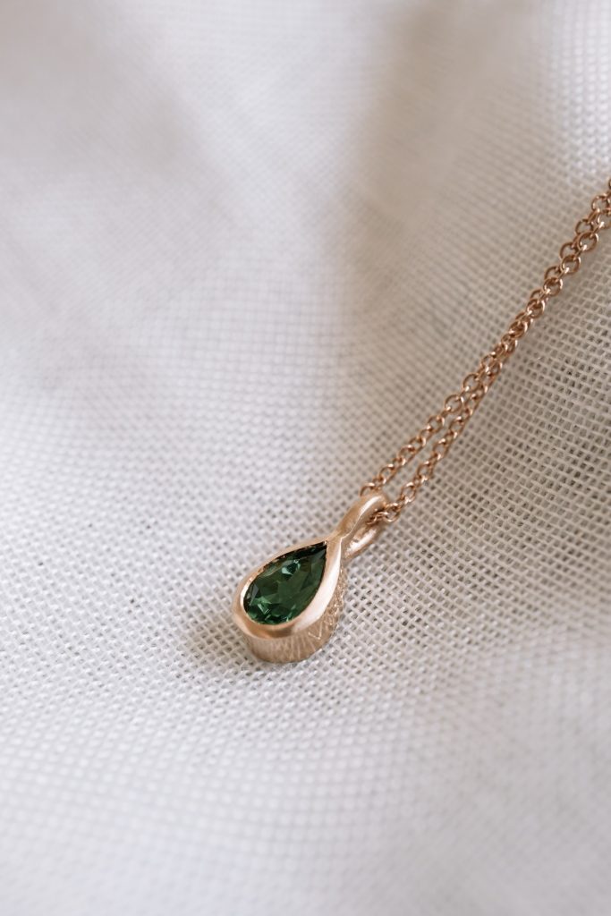 golden pendant with green gemstone